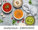 Small photo of Set of colored soups. Cream of mushroom soup, tomato soup, pumpkin soup and broccoli soup. Healthy food. Gray rustic background. View from above.