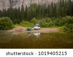 Morning landscape with a tent and 4wd car, the river bank and rocks in the background. Summer camping. Tourism. 