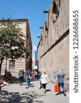 Small photo of BARCELONA, SPAIN - APRIL 17, 2018: Tourists walk past the medieval Cathedral of the Holy Cross and Saint Eulalia. Construction of the main building began in 1298.