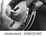 Small photo of mature, older man, male playing five string banjo outside in monochrome black and white close-up of hand and fingers bluegrass music