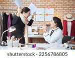 Small photo of Asian middle-aged female fashion designer and young teen trainee tailor celebrate and cheerful with dress design work success, gratify together in studio, happy costume boutique small business.