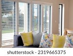 Small photo of Open white shutters in living room, with blue couch and yellow scatter cushions