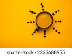 Black coffee in a cup with coffee beans around, close-up. Cup with black coffee on yellow background.