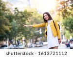 Small photo of Young Asian woman hailing a taxi ride. Beautiful charming woman hailing a taxi cab in the street. Businesswoman trying to hail a cab in the city. Tourist woman hailing a taxi