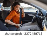 Young woman sitting on car seat and fastening seat belt, car safety concept. Woman fastens a seat belt in the car. Caucasian woman driver fastening car seat belt while sitting behind the wheel.