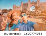 A couple in love arrived for their honeymoon in Dubai and takes a selfie in front of their hotel on the island of palm Jumeirah