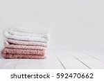 Stack of clean towels on wooden table in bathroom.