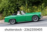 Small photo of Milton Keynes,UK-Sept 10th 2023: 1971 green MG Midget classic British sports car travelling on an English road.
