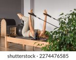 Small photo of Woman training pilates on the reformer bed. Reformer pilates studio machine for fitness workouts in gym. Fit, healthy and strong authentical body. Fitness concept