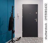 Small photo of Stylish and small home corridor with white and blue walls with molding and baseboards, patterned floor tiles, dark doors and simple, black clothes hanger