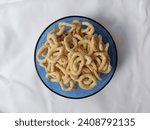 Small photo of Lanthing is a traditional Indonesian snack made from cassava that has been crushed, seasoned, and subsequently fried. Pile of lanting in a blue bowl isolated in white cloth background.