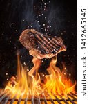 Small photo of Tasty beef steaks flying above cast iron grate with fire flames. Freeze motion barbecue concept.