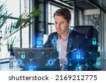 Small photo of Handsome businessman in suit at workplace working with laptop to defend customer cyber security. Concept of clients information protection and brainstorm. Padlock hologram over office background.