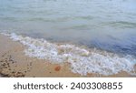 Small photo of The Foam Of Sea Waves Breaking On The Shore Of Tanjung Anda, Indonesia