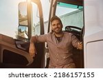 Small photo of Young happy truck driver about to hit the road. He is looking at camera.