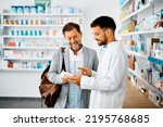 Small photo of Young pharmacist talking to male customer in a drugstore. Focus is on customer.