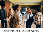 Small photo of Happy African American high school student walking through hallway with her friends and looking at camera.