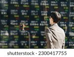 Small photo of See the electronic bulletin board on an outdoor stock board A businessman investor male in the 30s