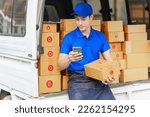 Small photo of Delivery man asia people checking portable delivery device with parcel box to customer home address. checking or confirm customer address and delivery time on mobile smart phone, call a mobile phone