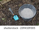 bucket of wood ash together with a shovel on arable soil. use of fertilizer and insecticide.