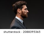 Small photo of Profile view of self confident bearded man looking with serious expression, unsmiling determined business man. Indoor studio shot isolated on black background