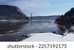 Small photo of Winter time slowly setting over the Mid Hudson region. Huge ice sheets flow underneath the Bear Mountain bridge. Billowing wind, a frigid breeze across the waters edge