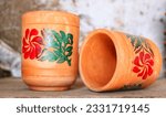 Small photo of Empty Handmade clay glass water lay on wood shelf, glass with multiclor flower,clay glass for drinking water ,source natural clay glass,brown clay water mug