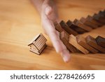 Small photo of Businessman hand protect home from domino effect, insurance and contingency plans concept