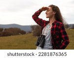 Young woman looking out over the horizon with binoculars hanging on her neck
