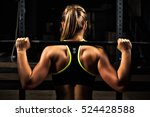 Back view young adult girl doing barbell squats in gym. Woman with muscular body doing lifting exercise.