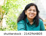 Small photo of Portrait of asian old woman 60s smile looking camera on green nature background.Senior 60 mother woman.Senior Adult Woman Smiling happy with retirement life.Dental care.Unaltered.Indian or Mexican.