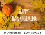 Thanksgiving lettering on a background of orange pumpkins and autumn leaves on wooden background