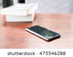 Smart phone with blank screen lying on wooden table,