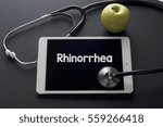 Small photo of Fresh green apple and stethoscope with word Rhinorrhea on digital tablet. Medical Concept.
