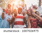 Multinational football supporters celebrating the begin of world competition - Happy multiracial people having fun together outside of stadium - Main focus on black man - Sport and bonding concept