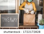 Young woman preparing takeaway organic food inside plastic free restaurant during Coronavirus outbreak time - Worker inside kitchen cooking food for online delivery service - Focus on right hand