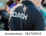 back of a coach's black shirt with the white word Coach written on it