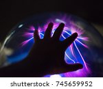 Man's hand touching plasma globe.