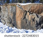 Granite rocks under a snow cover with traces of industrial stone cutters