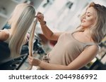 Hairdresser female making hair extensions to young woman with blonde hair in beauty salon. Professional hair extension