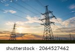 Small photo of silhouette of high voltage power lines against a colorful sky at sunrise or sunset.