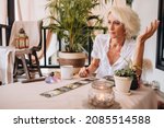 Middle-aged professional tarologist having session. Woman holding tarot cards and speaking with customer about his life