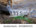 Small photo of concrete floor on which someone wrote 1995