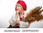 Small photo of Portrait of heerful funny adult mature woman solokha with sheaf of ears. Female model in clothes of national ethnic Slavic style. Stylized Ukrainian, Belarusian or Russian woman in comic photo shoot