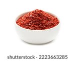 Small photo of a pile of red pepper flake or heap of red pepper powder coarse. korean chili ground Gochugaru in white bowl isolated on white background
