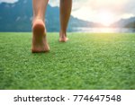 Young female legs walking towards the sunset on a ground grass with blur mountain and lake