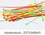 Several cable ties or tools for tying cables. Colored red, yellow, green and white. Made of plastic. Isolated white background.