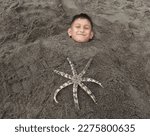 Small photo of Nanggroe Aceh Darussalam May 4, 2022 - a boy sleeping on his back and deliberately buried in beach sand, leaving only his head and starfish above his body