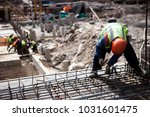 Construction worker. Сoncrete construction site: pillar, steel rebar. Contractor worker works with concrete slab steel cage. Construction site with builder worker. Concrete slab construction.