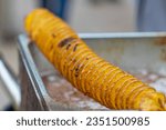 potato chips on a skewer. Spiral potatoes fried, on wooden sticks, spiral. Selling food at the market. Unhealthy fried food. Street food, a spiral fried potato on a stick.